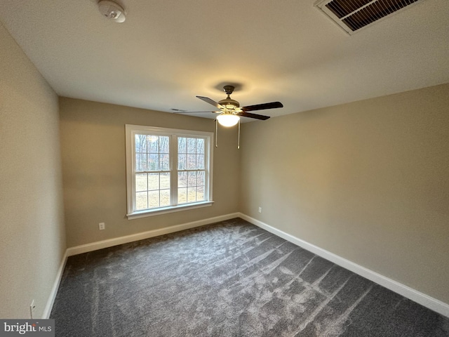 spare room featuring dark colored carpet, visible vents, baseboards, and ceiling fan