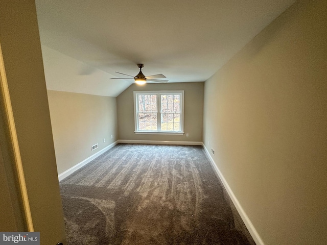 carpeted empty room featuring baseboards, a ceiling fan, and vaulted ceiling