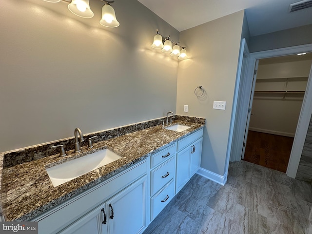 full bathroom featuring a sink, visible vents, baseboards, and a walk in closet