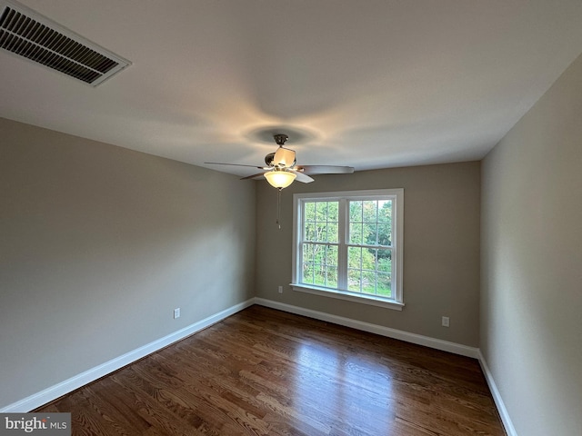 empty room with visible vents, baseboards, dark wood-style floors, and a ceiling fan