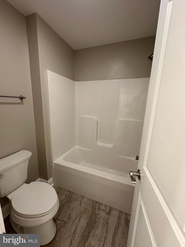 bathroom with shower / washtub combination, toilet, and marble finish floor