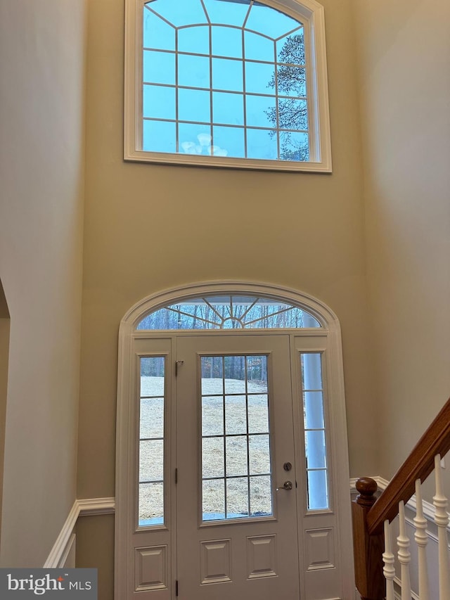 foyer entrance with stairway and a towering ceiling