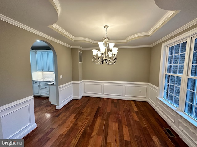 unfurnished dining area featuring dark wood finished floors, a raised ceiling, arched walkways, and visible vents