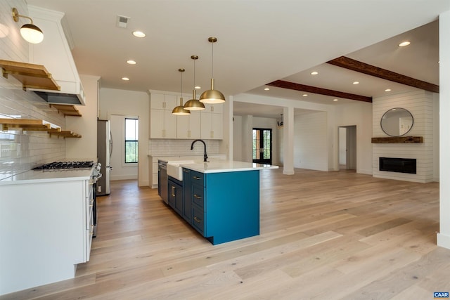 kitchen featuring a center island with sink, white cabinetry, hanging light fixtures, and light hardwood / wood-style floors