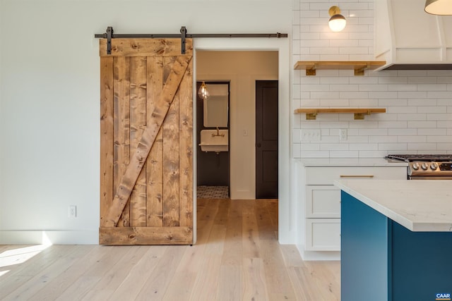 unfurnished dining area with a barn door, sink, and light hardwood / wood-style floors