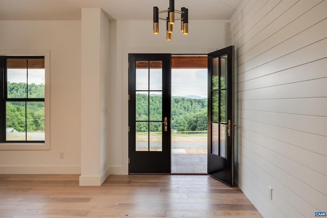 doorway with an inviting chandelier, light hardwood / wood-style floors, and french doors