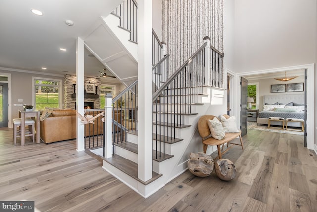 staircase featuring light hardwood / wood-style flooring, ornamental molding, and a fireplace