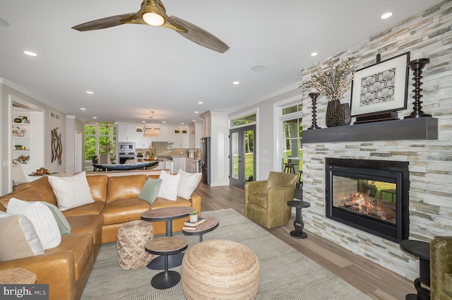 living room with a healthy amount of sunlight, ornamental molding, ceiling fan, and light wood-type flooring