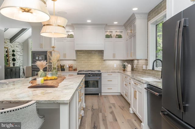 kitchen featuring appliances with stainless steel finishes, white cabinets, backsplash, light wood-type flooring, and sink