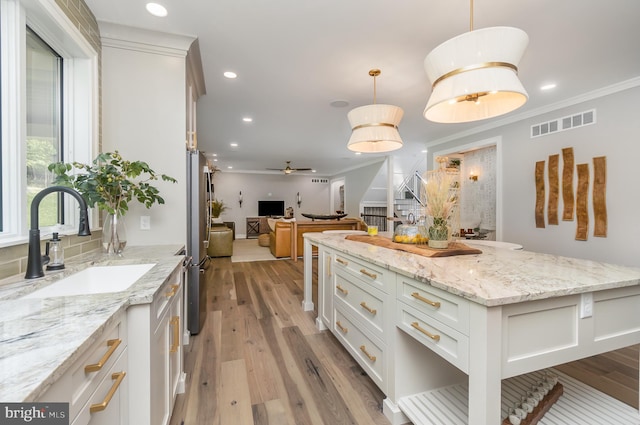 kitchen with white cabinetry, ornamental molding, ceiling fan, and pendant lighting