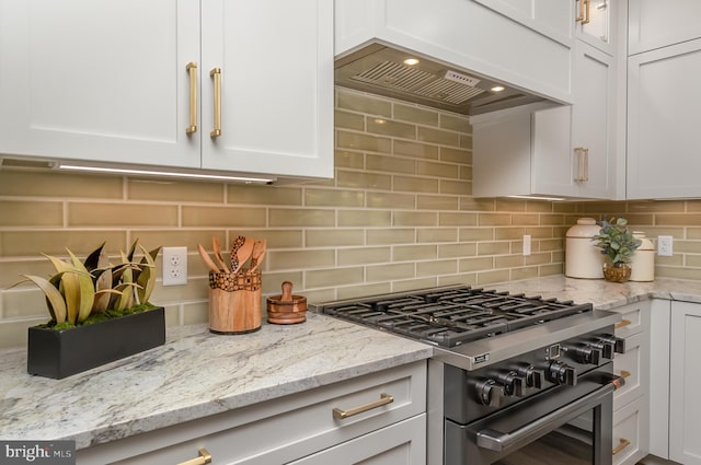 kitchen featuring white cabinets, backsplash, high end stainless steel range, and light stone counters