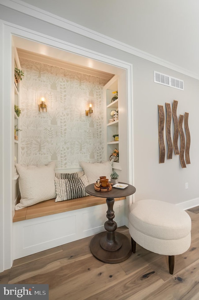 sitting room featuring crown molding, wood-type flooring, and built in shelves