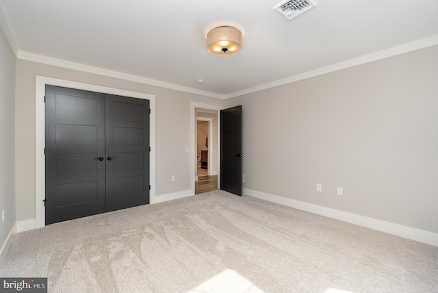 unfurnished bedroom featuring ornamental molding, light carpet, and a closet