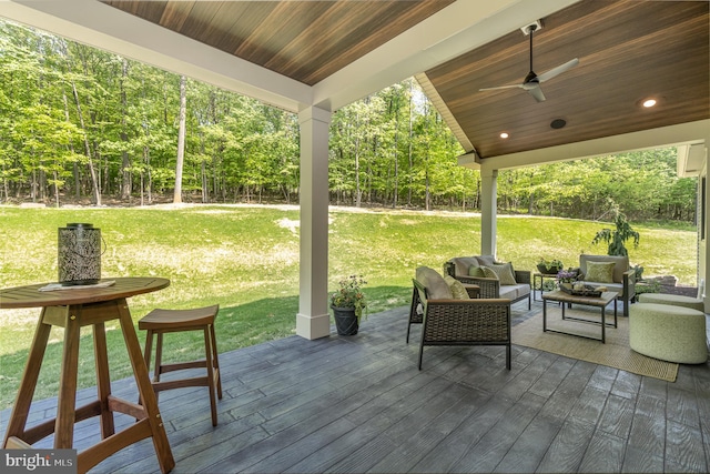 wooden deck with ceiling fan, outdoor lounge area, and a yard