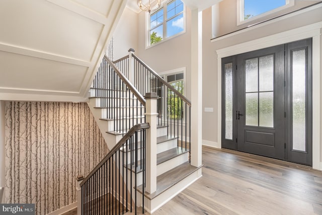 foyer featuring a towering ceiling, a notable chandelier, and light hardwood / wood-style floors