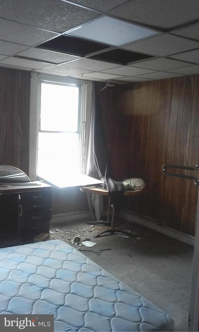 unfurnished bedroom featuring a paneled ceiling, wood walls, and multiple windows