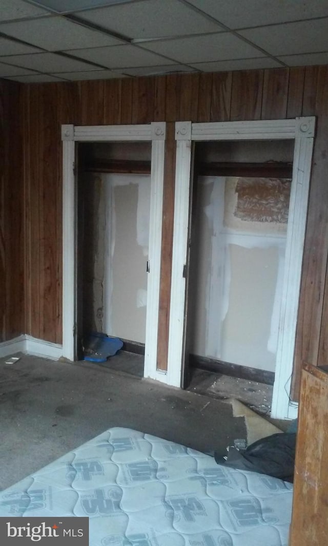 interior space featuring a paneled ceiling and wooden walls