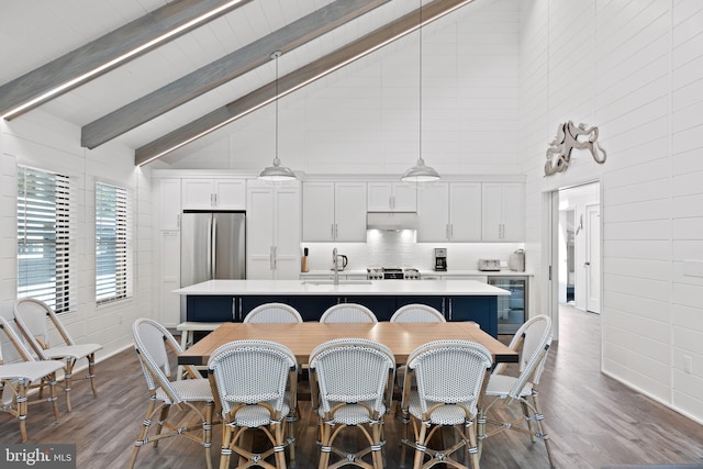 kitchen with white cabinets, a kitchen island with sink, decorative light fixtures, and high vaulted ceiling