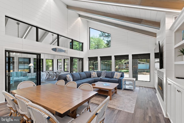 dining room with a healthy amount of sunlight, beam ceiling, dark hardwood / wood-style floors, and high vaulted ceiling