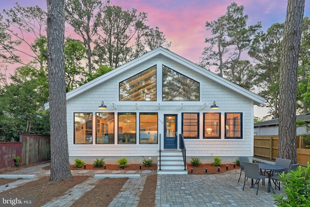 back house at dusk featuring a patio