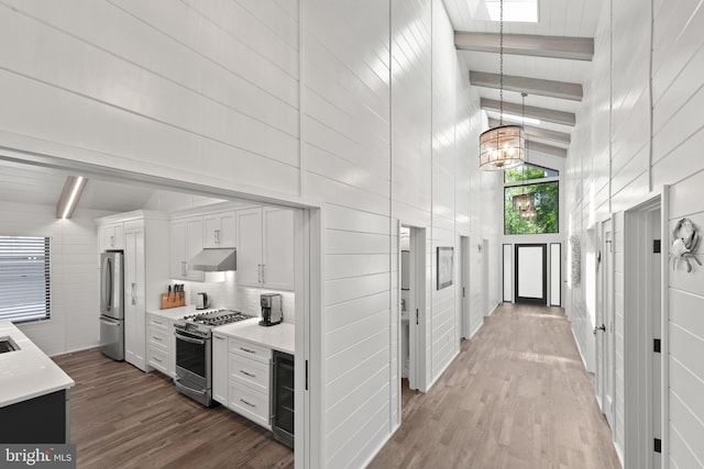 kitchen with stainless steel appliances, beamed ceiling, and hardwood / wood-style floors