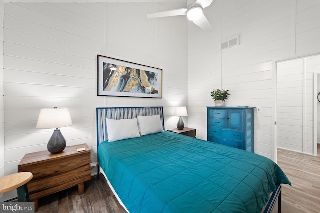 bedroom featuring a towering ceiling, ceiling fan, and hardwood / wood-style flooring