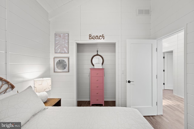 bedroom with wood-type flooring, beam ceiling, and high vaulted ceiling