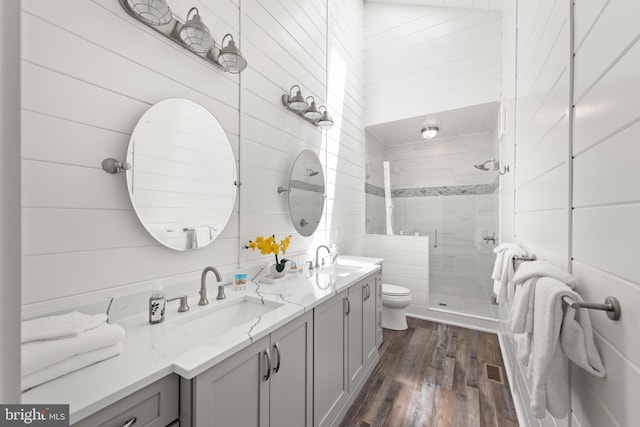 bathroom with wood-type flooring, vanity, a shower with shower door, and toilet