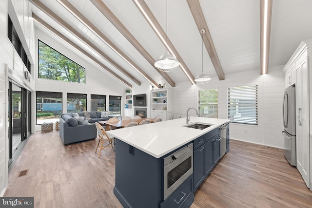 kitchen featuring an island with sink, appliances with stainless steel finishes, hanging light fixtures, and a healthy amount of sunlight