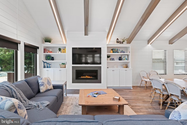 living room with light wood-type flooring, vaulted ceiling with beams, a fireplace, and wooden walls