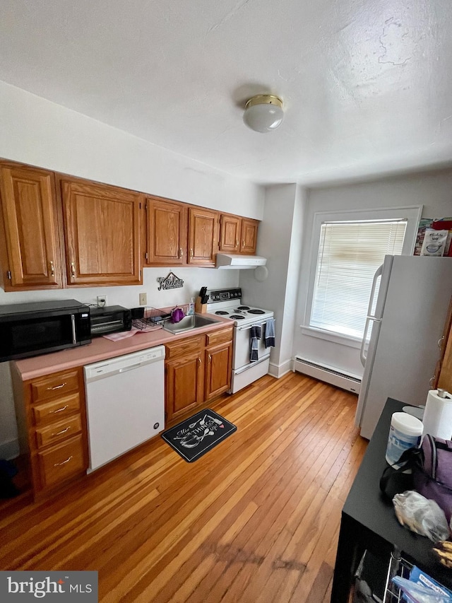 kitchen with sink, white appliances, light wood-type flooring, and a baseboard heating unit