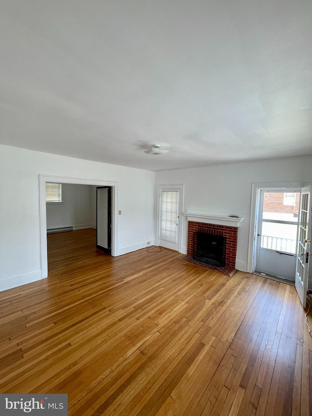 unfurnished living room with a fireplace, a baseboard heating unit, and hardwood / wood-style floors