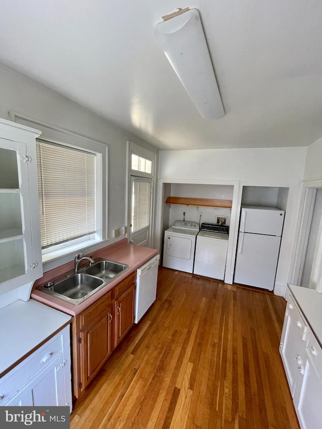 kitchen with light hardwood / wood-style flooring, washing machine and dryer, white appliances, and sink