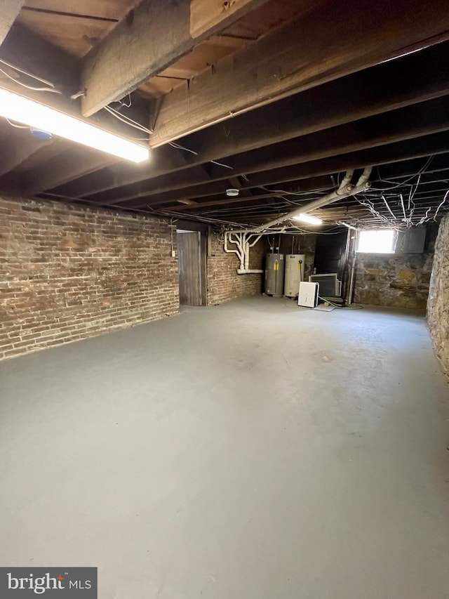 basement featuring water heater and brick wall