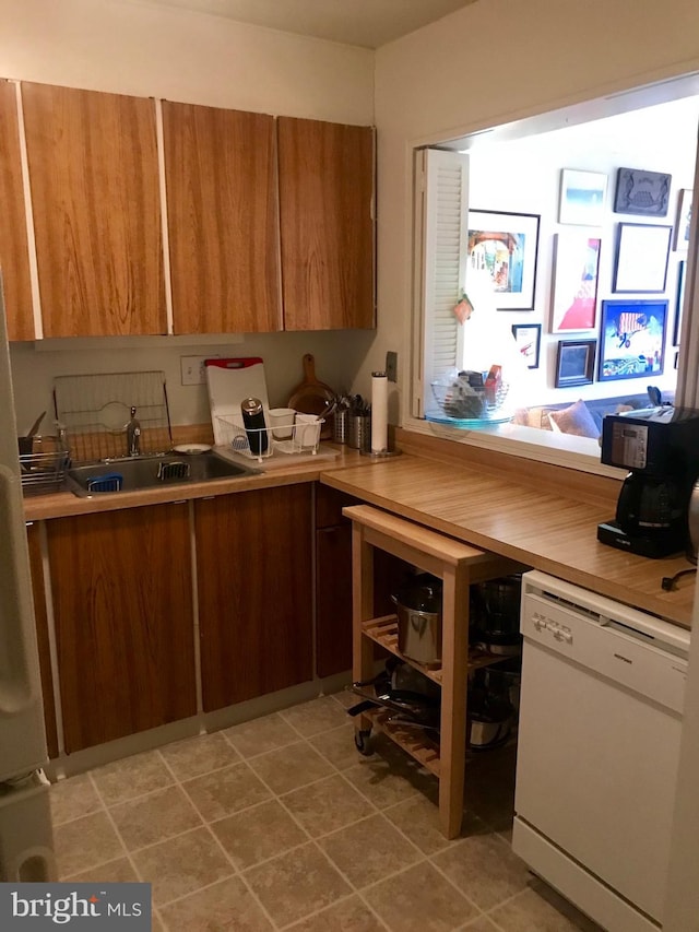 kitchen featuring sink, light tile floors, and white dishwasher