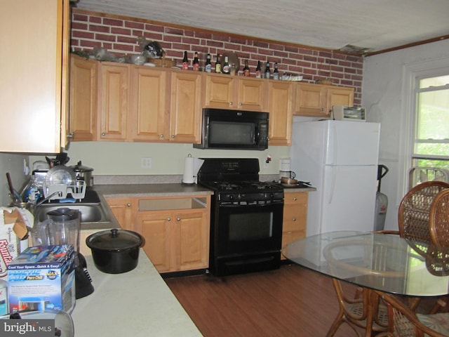 kitchen featuring brick wall, sink, light brown cabinetry, and black appliances