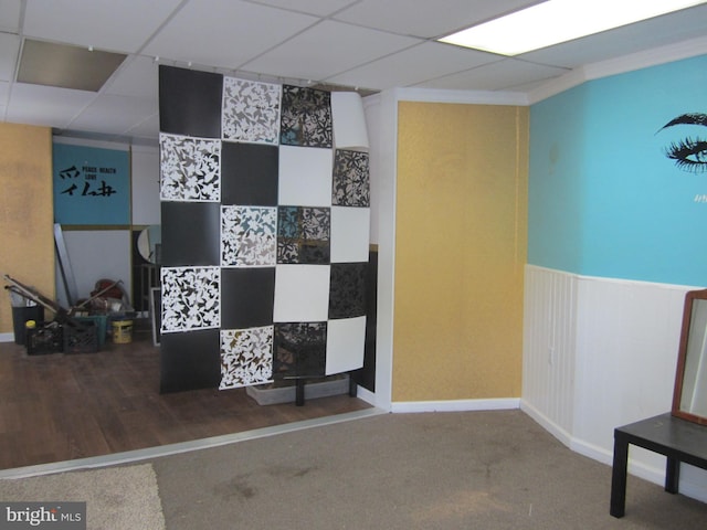 interior space with a paneled ceiling and dark colored carpet