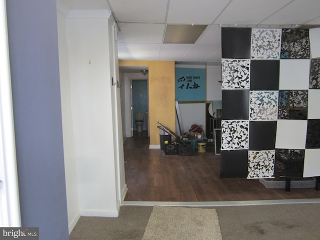 hallway featuring dark carpet and a drop ceiling