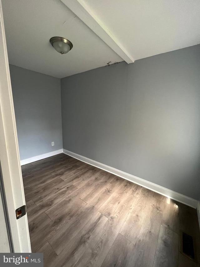 unfurnished room featuring beam ceiling and dark hardwood / wood-style flooring