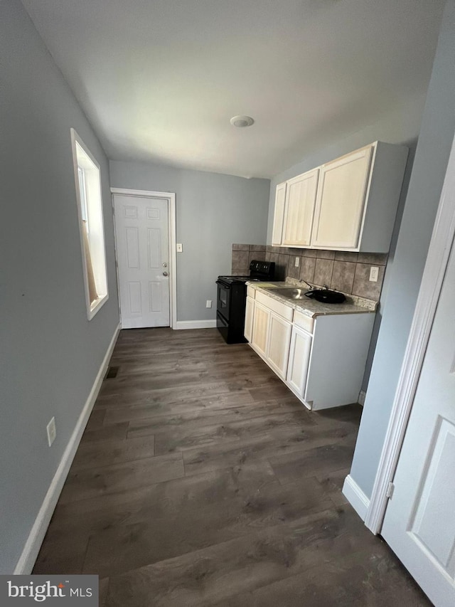 kitchen with black range with electric stovetop, tasteful backsplash, dark hardwood / wood-style floors, and white cabinets