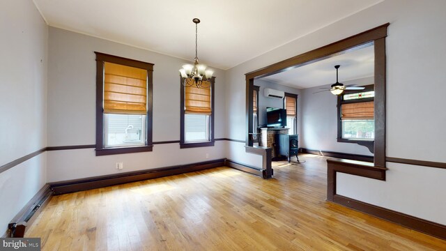 unfurnished room featuring a wall unit AC, a baseboard radiator, light hardwood / wood-style flooring, and ceiling fan with notable chandelier