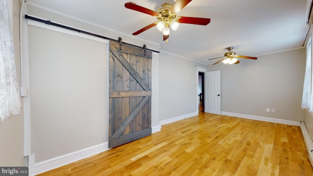 empty room featuring a barn door, light hardwood / wood-style flooring, ornamental molding, and ceiling fan