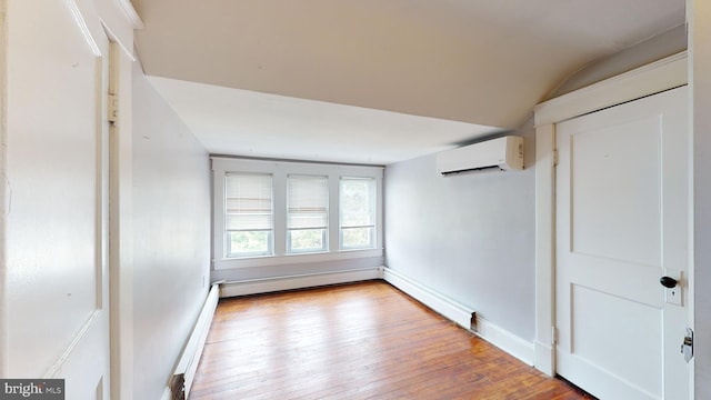 unfurnished room with a wall mounted air conditioner, light hardwood / wood-style floors, a baseboard radiator, and vaulted ceiling