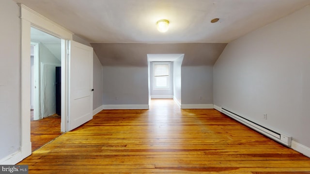 bonus room with a baseboard heating unit, light hardwood / wood-style flooring, and vaulted ceiling