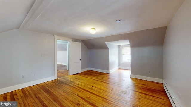 bonus room featuring lofted ceiling, light hardwood / wood-style floors, and a baseboard radiator