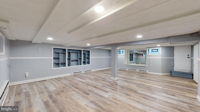 basement featuring a baseboard radiator and light hardwood / wood-style flooring