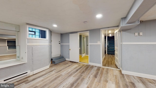 basement with light hardwood / wood-style floors and baseboard heating