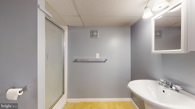 bathroom with sink, a drop ceiling, an enclosed shower, and hardwood / wood-style flooring