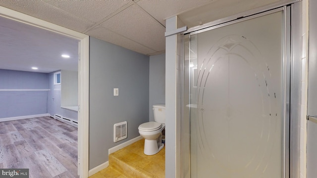 bathroom with a drop ceiling, toilet, a baseboard heating unit, and hardwood / wood-style flooring