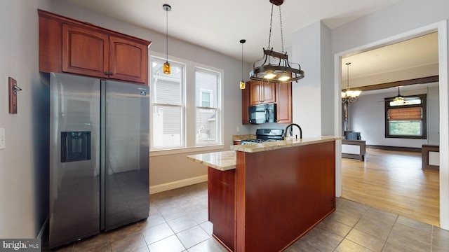 kitchen with stove, ceiling fan with notable chandelier, stainless steel refrigerator with ice dispenser, light wood-type flooring, and light stone counters